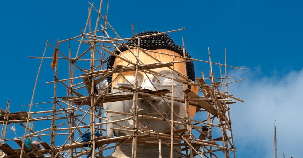 A large Buddha statue under construction with bamboo scaffolding in Vietnam, showcasing cultural craftsmanship.